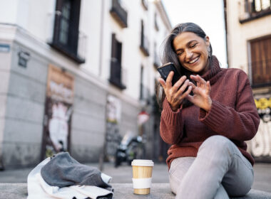 woman smiling at her phone outside