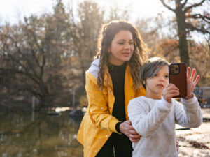 A woman helps her child use a phone