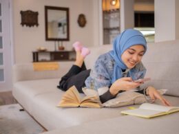 A student in a headscarf looks at her phone