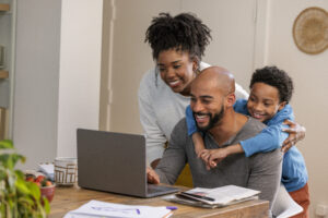 A smiling family at home looks at a computer.