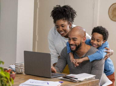 A smiling family at home looks at a computer.