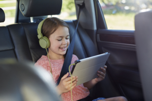 a picture of a girl using a tablet in a car