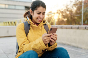 A woman uses her phone to check social media and text friends in public.