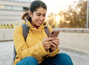 A woman uses her phone to check social media and text friends in public.