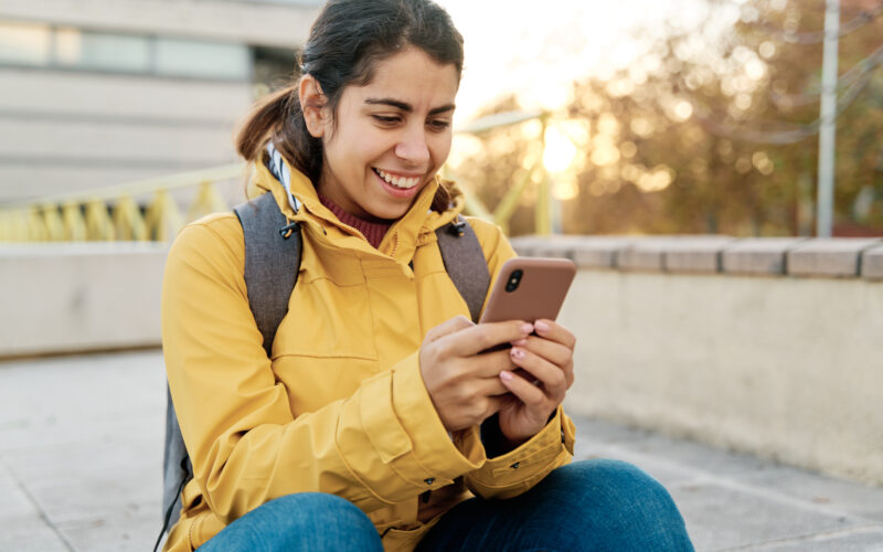 A woman uses her phone to check social media and text friends in public.