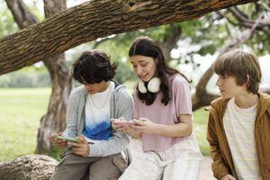 Teenagers on phones in park