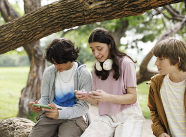 Teenagers on phones in park