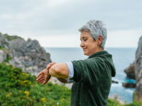 Mature woman near the ocean looking at her smartwatch