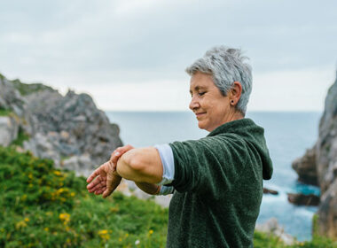 Mature woman near the ocean looking at her smartwatch
