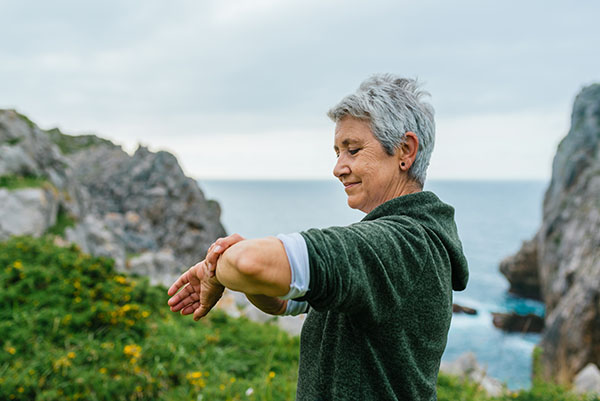 Mature woman near the ocean looking at her smartwatch