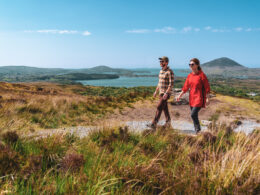 A couple hikes along a scenic trail through the rolling hills, with expansive views of lakes and distant peaks