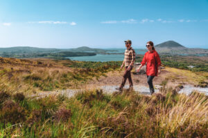A couple hikes along a scenic trail through the rolling hills, with expansive views of lakes and distant peaks
