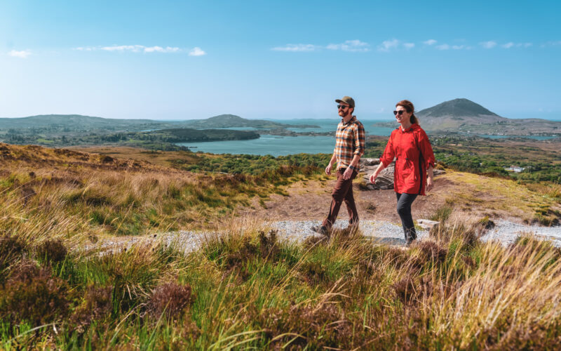 A couple hikes along a scenic trail through the rolling hills, with expansive views of lakes and distant peaks