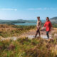 A couple hikes along a scenic trail through the rolling hills, with expansive views of lakes and distant peaks