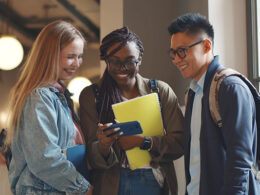 College students smiling at something on a smartphone