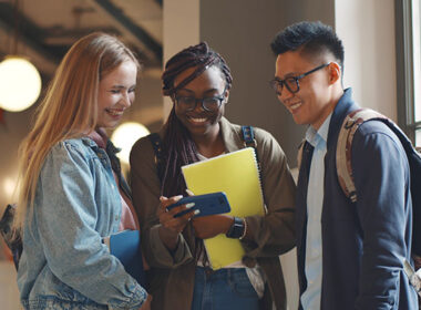College students smiling at something on a smartphone