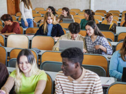 College students in a classroom looking at laptops.