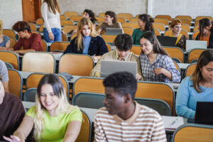 College students in a classroom looking at laptops.
