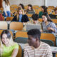 College students in a classroom looking at laptops.