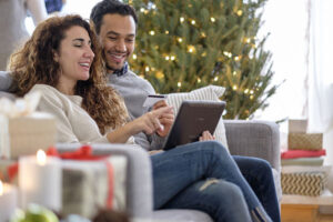 Couple shopping with digital tablet on sofa at home during the Christmas holiday,
