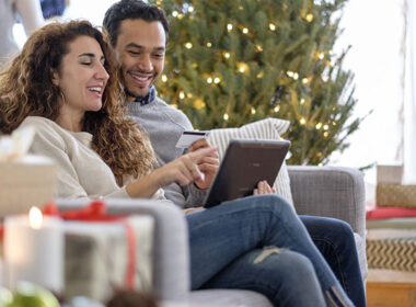 Couple shopping with digital tablet on sofa at home during the Christmas holiday,