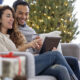 Couple shopping with digital tablet on sofa at home during the Christmas holiday,