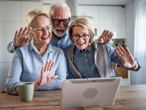 Senior couple and friend video calling family with tablet