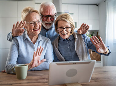 Senior couple and friend video calling family with tablet
