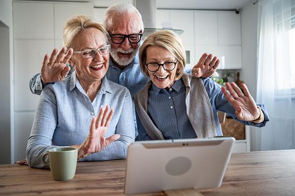 Senior couple and friend video calling family with tablet