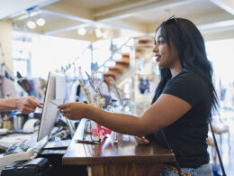 Young woman paying cashier in clothing store with credit card