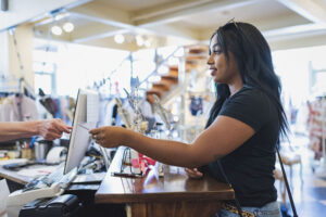 Young woman paying cashier in clothing store with credit card