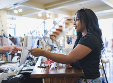 Young woman paying cashier in clothing store with credit card