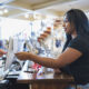 Young woman paying cashier in clothing store with credit card