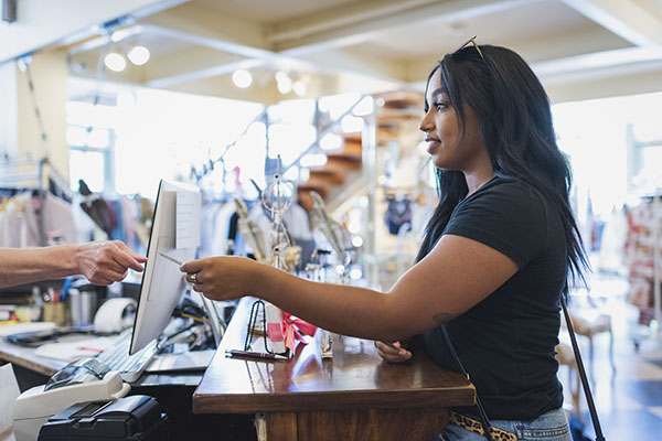 Young woman paying cashier in clothing store with credit card