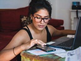 Latina woman working on her personal finances, with her bank statements, bills and computer.