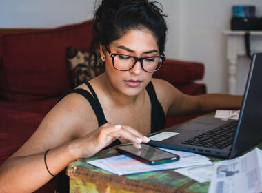 Latina woman working on her personal finances, with her bank statements, bills and computer.