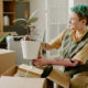 Young adult Caucasian woman with prosthetic arm unpacking cardboard box