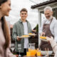 bearded father and young adult son holding plates, mother and teenage sister on foreground, backyard