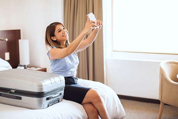Pretty young businesswoman taking a selfie after arriving at a hotel to remember her first business trip