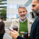 Mature men coworkers smiling and chatting outside office