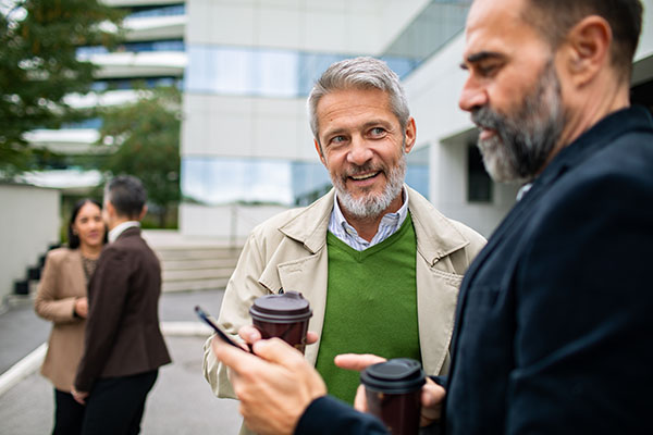 Mature men coworkers smiling and chatting outside office