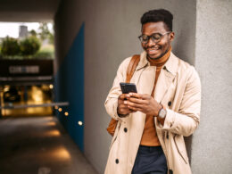 Young black businessman waiting for an Uber, using mobile phone for communication.