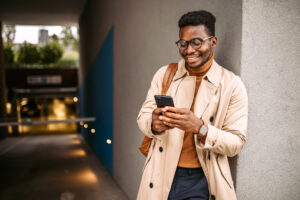 Young black businessman waiting for an Uber, using mobile phone for communication.