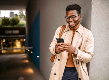 Young black businessman waiting for an Uber, using mobile phone for communication.