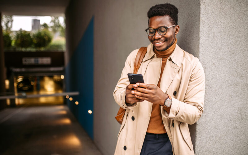 Young black businessman waiting for an Uber, using mobile phone for communication.