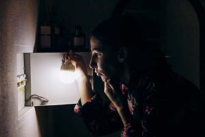Lights and electricity go out in apartment during blackout. A girl stands near the fuse box and thinks.