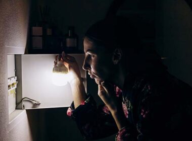 Lights and electricity go out in apartment during blackout. A girl stands near the fuse box and thinks.