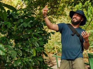Happy bearded traveler taking a selfie with smartphone on a lush tropical forest trail