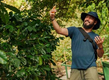 Happy bearded traveler taking a selfie with smartphone on a lush tropical forest trail