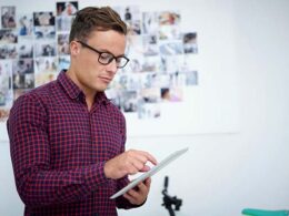 Serious young photographer with tablet computer uploading new photos on social media